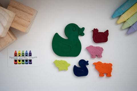 crayons in the shapes of a large and small sitting duck, sitting chicken, standing cow with bill open, standing sheep and standing pig