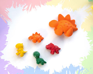 A large, orange stegosaurus crayon with 4 smaller crayons, a brachiosaurus, a triceratops, a stegosaurus, and a t-rex