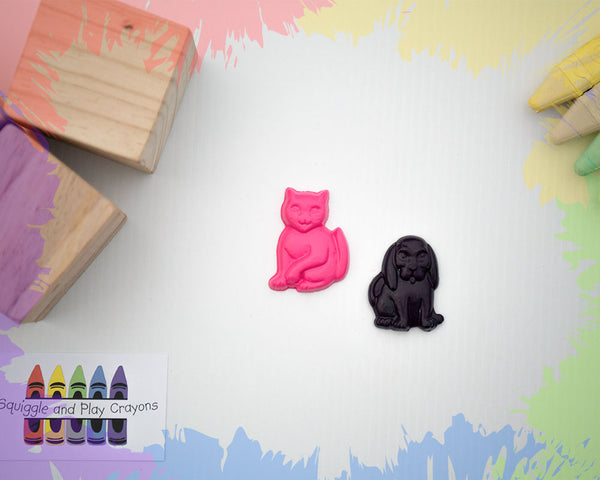 2 small crayons, 1 a hot pink sitting car with a paw raised, and the other a black sitting long-eared dog