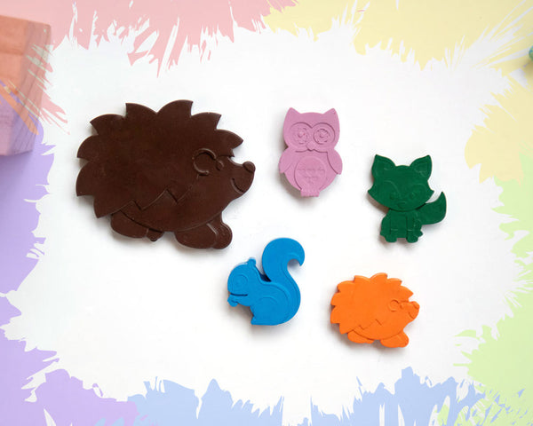 A large, brown hedgehog crayon, with 4 small crayons in the shape of a fox, a hedgehog, an owl, and a squirrel