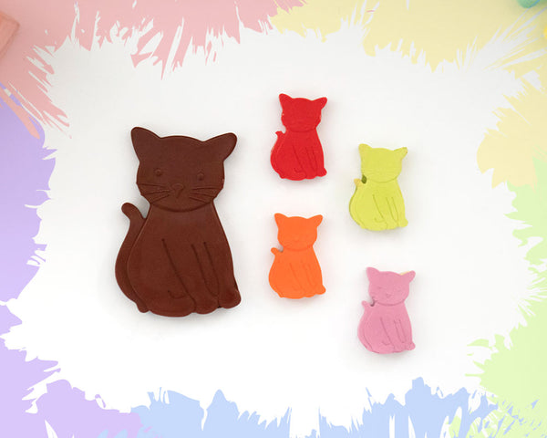 A large, brown crayon in the shape of a sitting cat, with 4 smaller versions